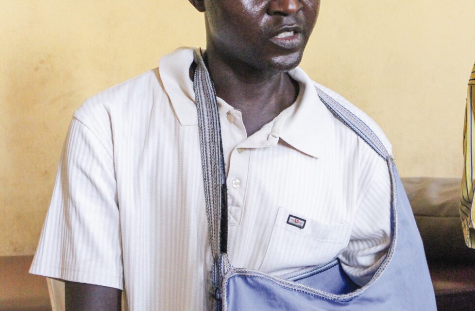 a man sits in a chair with his arm in a sling